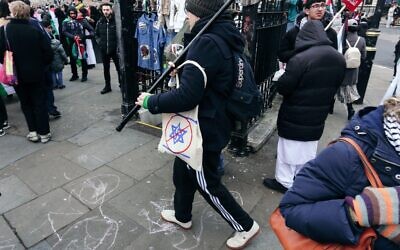 A man carries a tote bag showing a Swastika/Star of David design, struck through in red. © Amstel Adams/ Alamy Live News