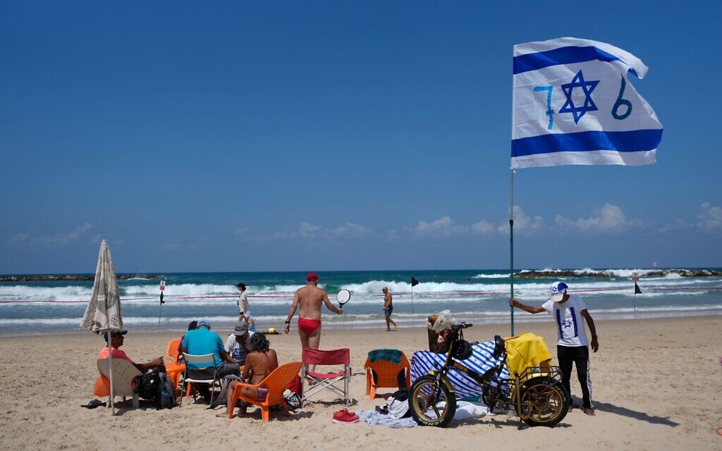 A man places an Israeli flag on the beach during Israel's Independence Day celebrations in Tel Aviv