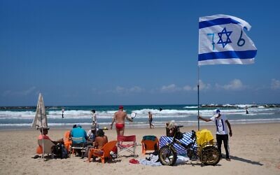 A man places an Israeli flag on the beach during Israel's Independence Day celebrations in Tel Aviv, Tuesday, May 14, 2024.