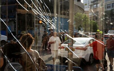 People are seen through a broken window next to the scene of an explosive drone attack in Tel Aviv, Israel, Friday, July 19, 2024.
