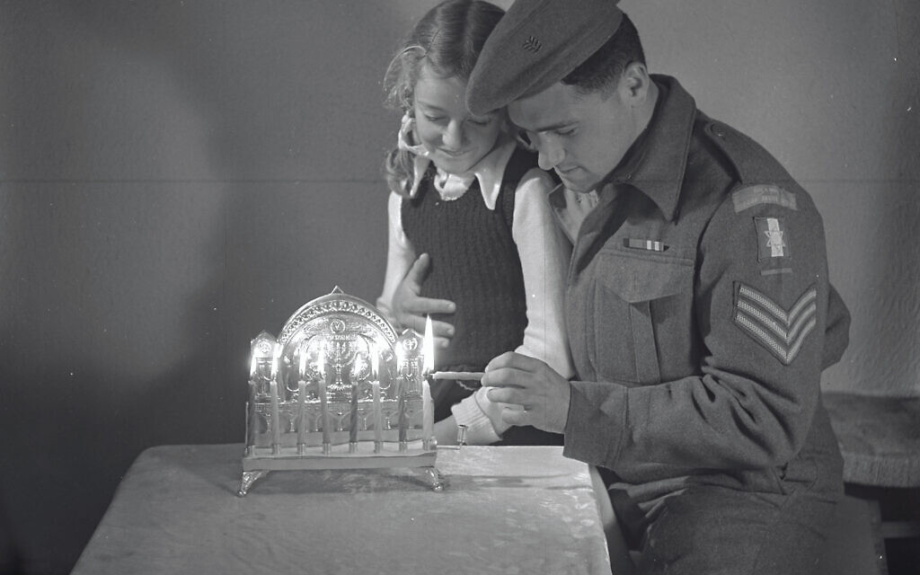 A young girl lighting the Hanukkah candles with a soldier from the Jewish Brigade, whose members had just liberated Europe at the end of World War II. Jerusalem, 1945 A young girl lighting the Hanukkah candles with a soldier from the Jewish Brigade, whose members had just liberated Europe at the end of World War II. Jerusalem, 1945