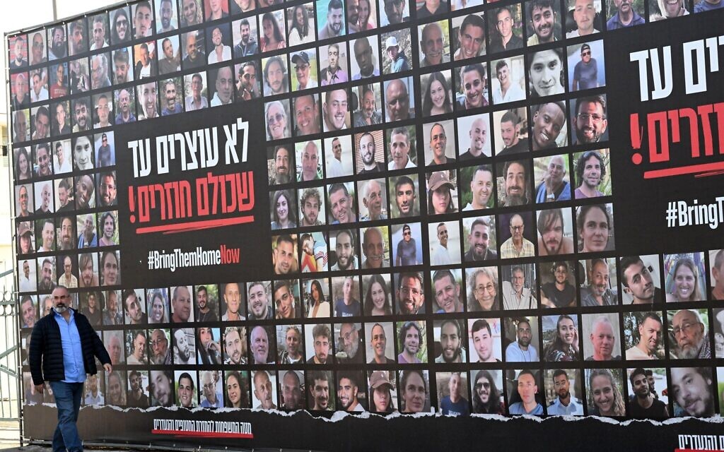A man walks past a large billboard with photos of Israeli hostages kidnapped by Hamas on Wednesday, January 15, in Jerusalem.