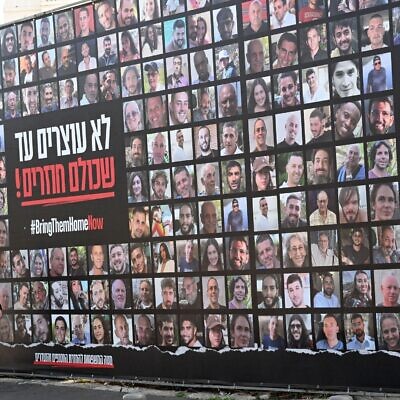 A man walks past a large billboard with photos of Israeli hostages kidnapped by Hamas on Wednesday, January 15, in Jerusalem.
