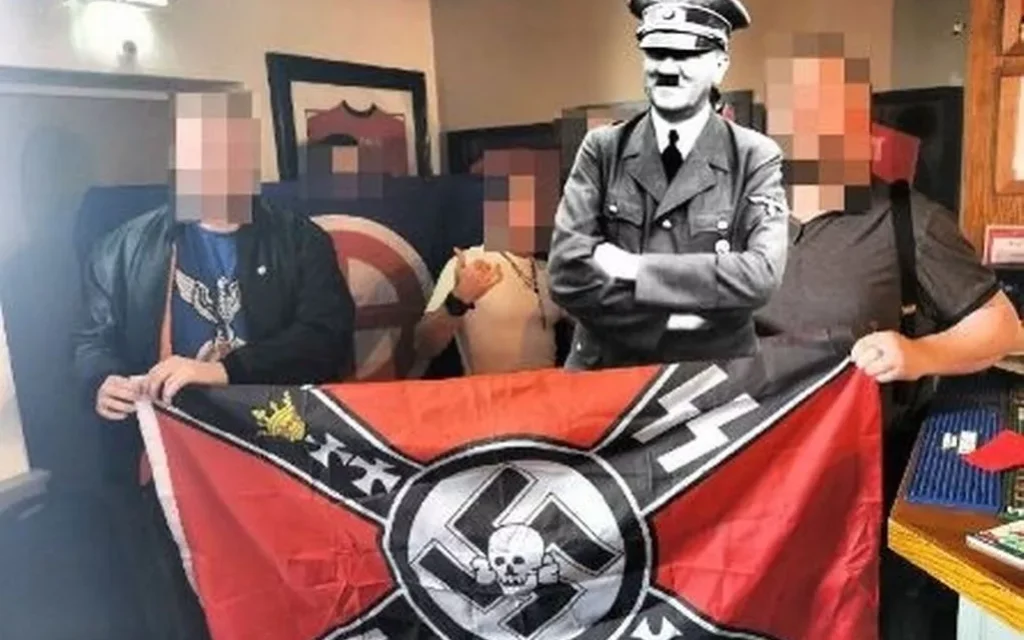 British Movement members pose with a Nazi flag at an Oldham pub. Hitler image digitally added. Photo Credit: British Movement