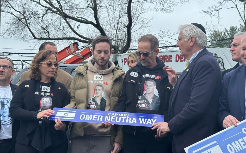 Omer Neutra’s family hold the newly unveiled street sign in his honour during the dedication ceremony in Plainview, Long Island.