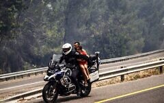 A police officer on a motorcycle rescues a father and his child from the raging wildfires. Israel, May 2025. Twitter/X