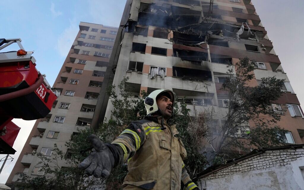 A firefighter calls out his colleagues at the scene of an explosion in a residence compound in northern Tehran, Iran, Friday, June 13, 2025. (AP Photo/Vahid Salemi)