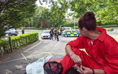 A Palestine Action protester in handcuffs watches as police gather outside Elbit Systems’ Bristol HQ