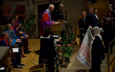 A student holds a banner while crossing the stage during Edinburgh’s graduation ceremony. Photo taken from X