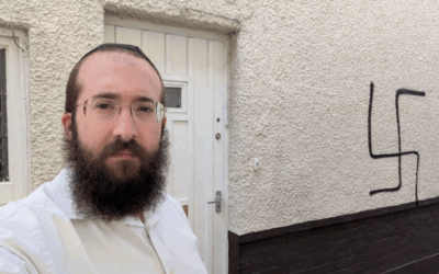 Rabbi Alperowitz next to the Nazi symbol daubed on his home