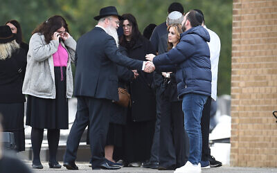 Rabbi Daniel Walker shakes hands with members of the congregation after the funeral of Adrian Daulby at Agecroft Jewish Cemetery in Salford, Manchester.