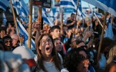 People react as they gather to watch a live broadcast of Israeli hostages released from Gaza at a plaza known as hostages square in Tel Aviv, Israel, Monday, Oct. 13, 2025. The release took place as part of a cease-fire agreement between Israel and Hamas. (AP Photo/Emilio Morenatti)