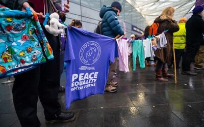 Supporters of Friends of Standing Together display children’s clothing and peace messages during the Human Rights Day vigil at King’s Cross. Credit:
Abraham Dein