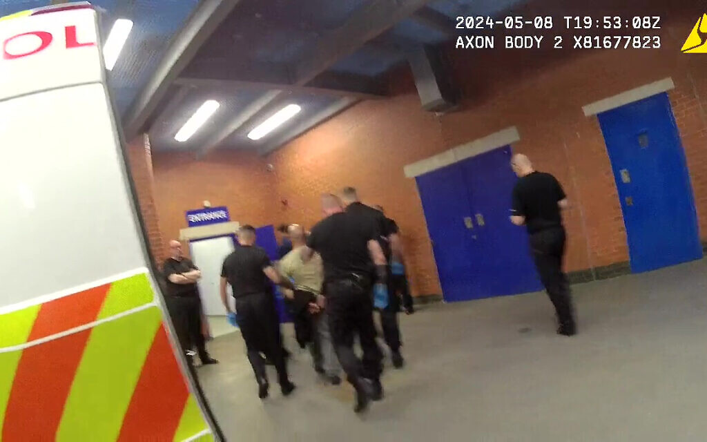 Screen grab taken from handout video dated 08/05/24 issued by Greater Manchester Police of Amar Hussein (centre, in light coloured top) being brought into custody.