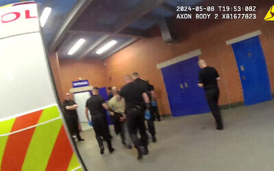 Screen grab taken from handout video dated 08/05/24 issued by Greater Manchester Police of Amar Hussein (centre, in light coloured top) being brought into custody.