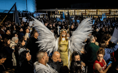 A woman wearing wings stands above the crowd during a protest rally in Tel Aviv on Saturday Jan 31 2026. Tens of thousands of Arab and Jewish protesters turned out in Tel Aviv Saturday night for a massive rally, accusing the government of neglecting its Arab citizens and allowing violence to run rampant in the community. Photo by Eyal Warshavsky