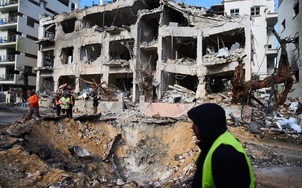 Rescue workers and military personnel survey the scene of a direct hit a day after an Iranian missile struck in Tel Aviv, Israel