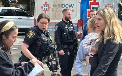 A woman gathers children as law enforcement respond to a call at Temple Israel synagogue on Thursday, March 12, 2026, in West Bloomfield Township, Mich. (AP Photo/Corey Williams)