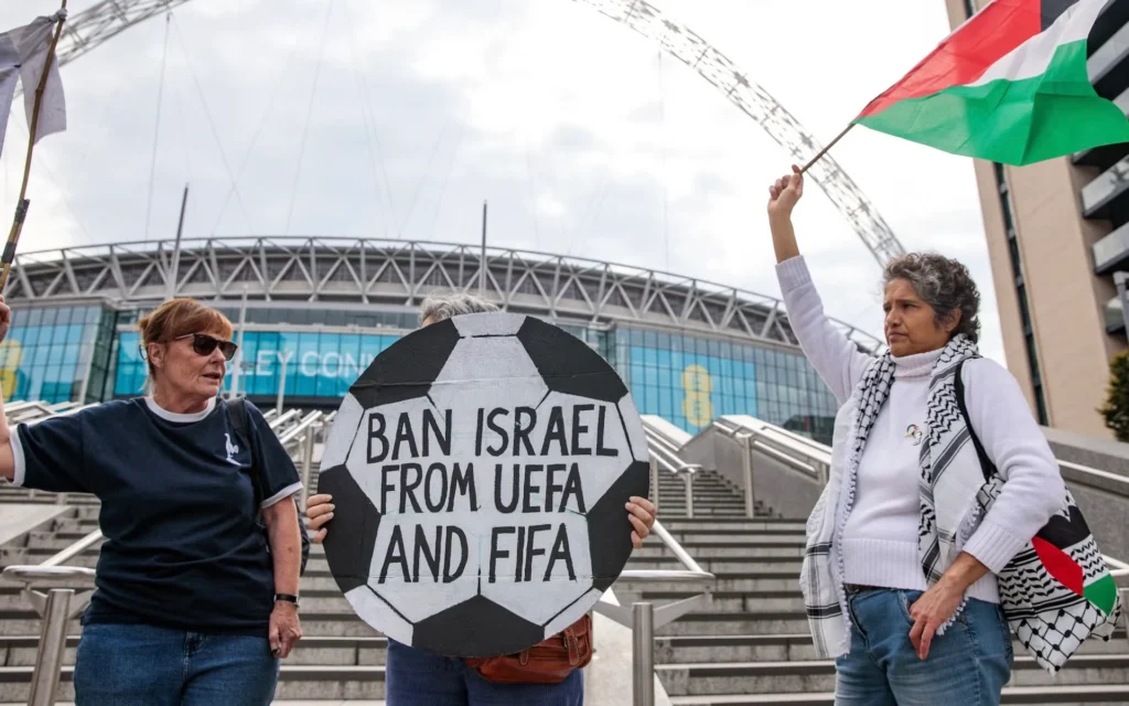 Pro-Palestinian activists protest with a football-shaped sign and a Palestinian flag outside Wembley Stadium to demand that the Football Association issue a public statement calling for the Israeli Football Association (IFA) to be suspended from participation in UEFA and FIFA tournaments, on October 2, 2025 in London, United Kingdom. (Mark Kerrison/In Pictures via Getty Images via JTA)