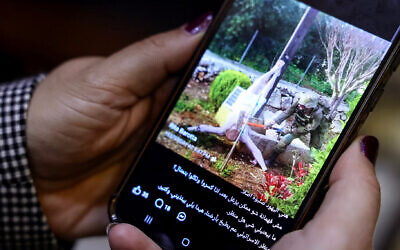 A woman checks a social media post on her mobile phone featuring an image that appears to show an Israeli soldier hitting a statue of Jesus Christ in the southern Lebanese Christian village of Debl, in Beirut on April 20, 2026. (Anwar AMRO / AFP)