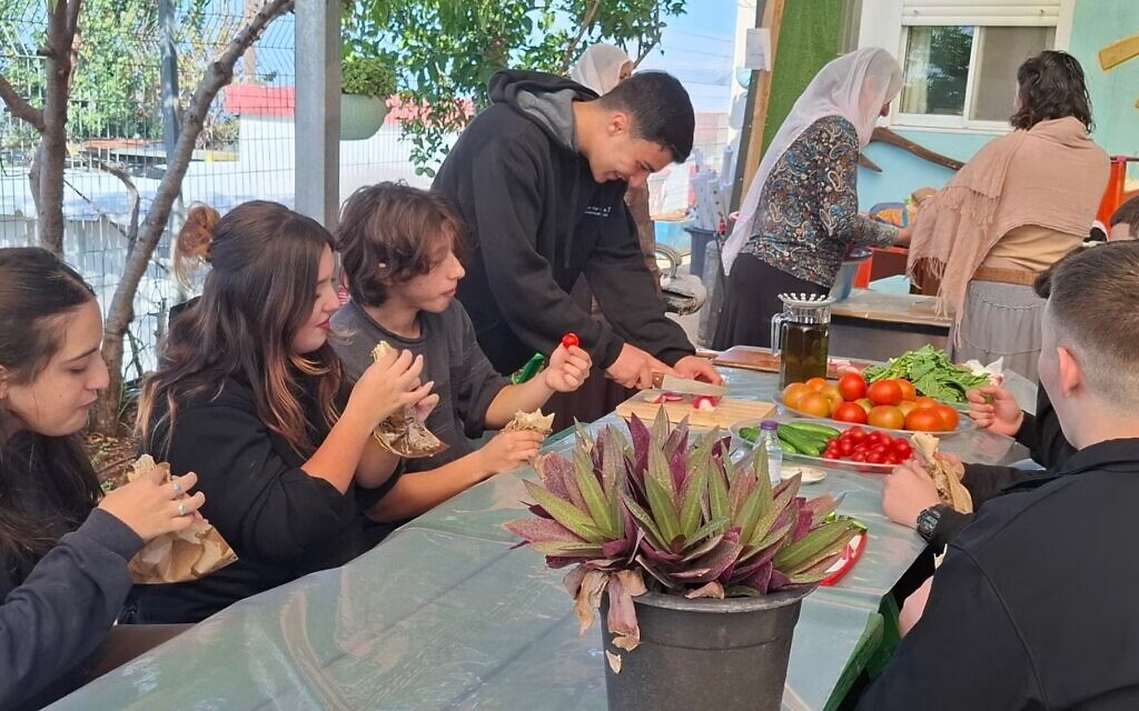 Jewish and Druze students come together and share bread and vegetables grown at a farm extension of the Amal high school in Yanuh Jat in November 2025. (Elana Sztokman)