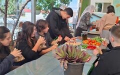 Jewish and Druze students come together and share bread and vegetables grown at a farm extension of the Amal high school in Yanuh Jat in November 2025. (Elana Sztokman)