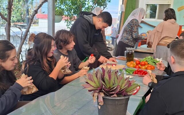 Jewish and Druze students come together and share bread and vegetables grown at a farm extension of the Amal high school in Yanuh Jat in November 2025. (Elana Sztokman)