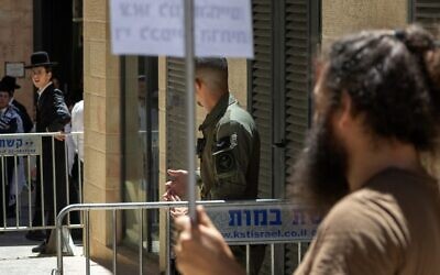 Haredi protesters and secular counter-protesters are separated by police outside Cafe Basimta in Jerusalem, July 18, 2026. (Theia Chatelle)