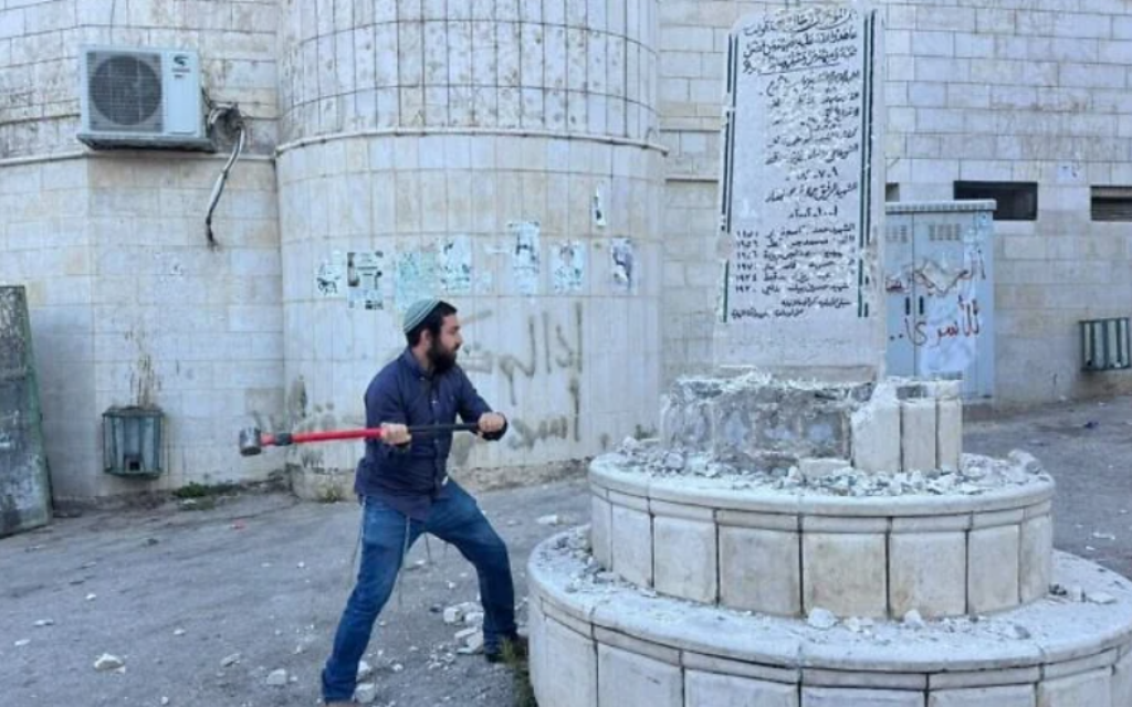 A picture released by Zvi Sukkot's office, showing the far right MK smashing a memorial in the Palestinian village of Madama