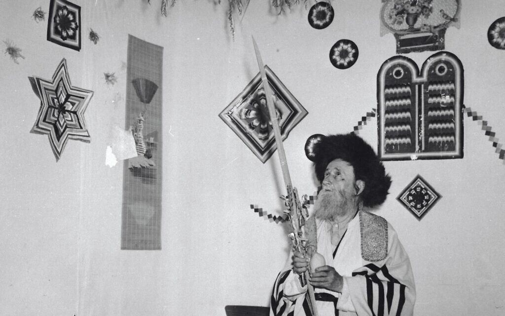 A Hasidic man performs the mitzvah of the Four Species inside a sukkah in Jerusalem, 1959. Photo credit - Avraham Malevsky, KKL-JNF Photo Archive