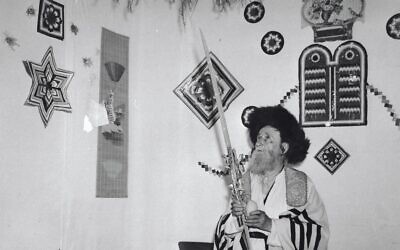 A Hasidic man performs the mitzvah of the Four Species inside a sukkah in Jerusalem, 1959. Photo credit - Avraham Malevsky, KKL-JNF Photo Archive