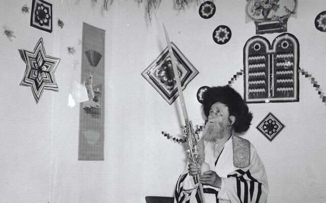 A Hasidic man performs the mitzvah of the Four Species inside a sukkah in Jerusalem, 1959. Photo credit - Avraham Malevsky, KKL-JNF Photo Archive