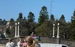 A man displays a Palestinian flag from a bridge near the site of the Bondi Beach Chanukah terror attack. (Credit: AJA)