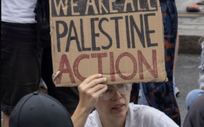 A demonstrator holds a placard reading “We Are All Palestine Action” during a protest against the group’s proscription.